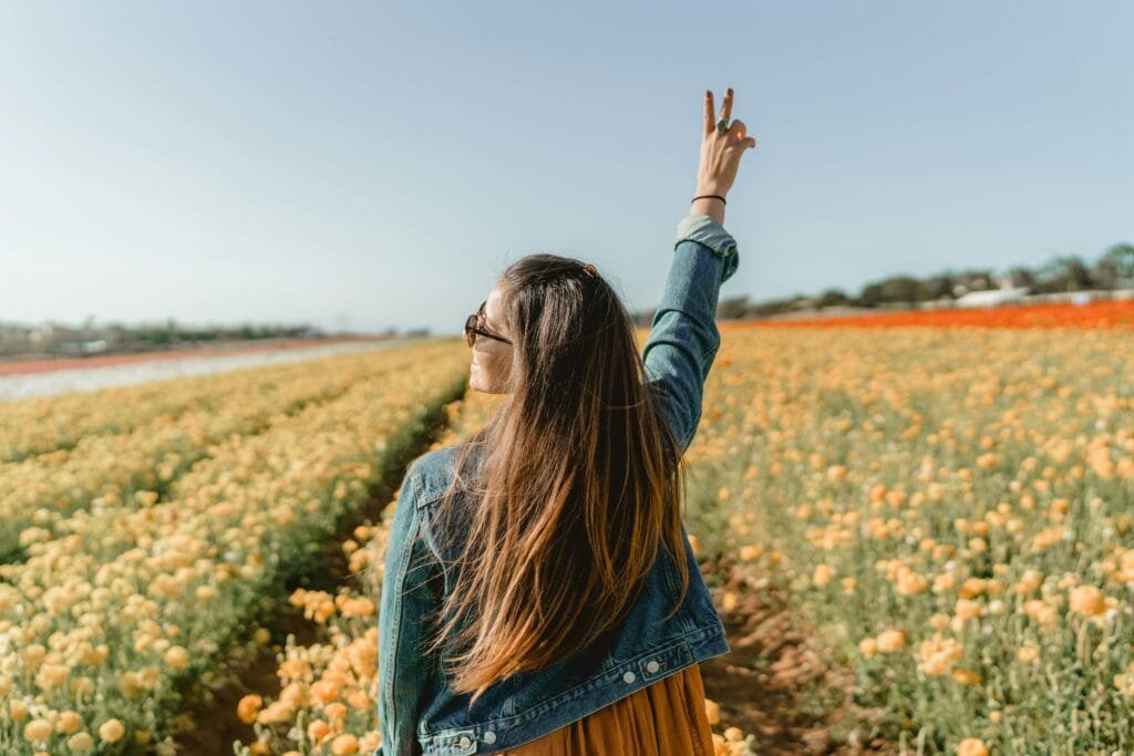 Finding Balance: Navigating Relationships & Personal Growth A woman enjoying a sunny day in a vivid yellow flower field in Carlsbad, CA.