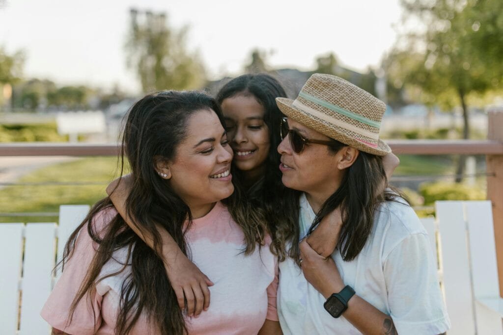 Happy family moment with three women outdoors in summer, embracing and smiling.