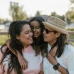 Happy family moment with three women outdoors in summer, embracing and smiling.